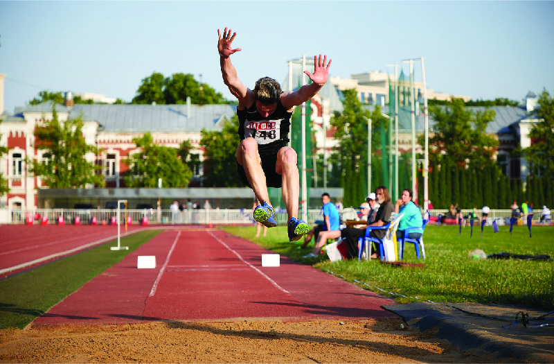 Спортсмен прыгает в длину, завис в воздухе